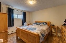 Bedroom featuring wood-finish flooring, a window with blinds, and neutral wall tones - 