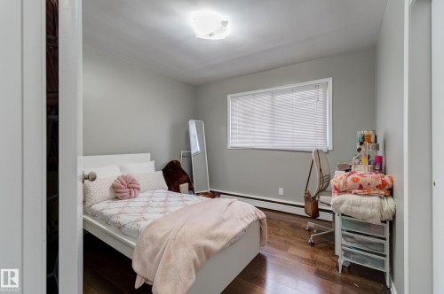 Bedroom featuring wood-finish flooring, light grey painted walls, a flush-mount ceiling light fixture, and a window with blinds - 9749 88 Avenue, Edmonton, AB - Indoor Photo Showing Bedroom