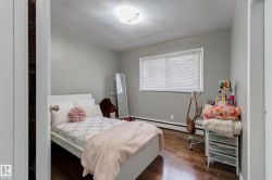 Bedroom featuring wood-finish flooring, light grey painted walls, a flush-mount ceiling light fixture, and a window with blinds - 