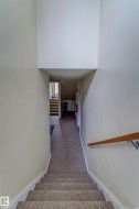 Carpeted staircase with a wood handrail leading to a carpeted hallway - 