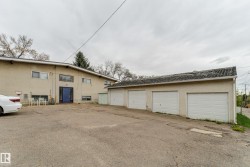 Expansive paved parking area with a four-stall detached garage featuring individual white overhead doors - 