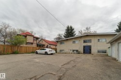 Rear exterior featuring a blue entrance door, multiple windows, and an asphalt parking area - 