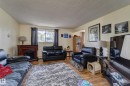 Spacious living area featuring wood-finish flooring, a decorative fireplace, and ample natural light from a window with dark curtains - 9749 88 Avenue, Edmonton, AB  - Indoor Photo Showing Living Room 