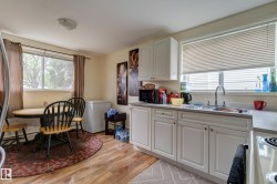 Kitchen area featuring light wood-finish flooring, white cabinetry, and a double basin sink - 
