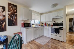 Kitchen featuring white cabinetry, gray countertops, wood-finish flooring, a window with horizontal blinds, and a built-in oven with overhead ventilation - 