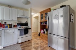 Kitchen featuring white cabinetry, white countertops, built-in range with overhead exhaust, and wood-finish flooring - 
