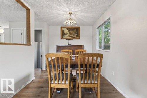 Dining area featuring warm wood-finish flooring, a window offering natural light, and a ceiling-mounted light fixture - 123 Grandin Drive, Morinville, AB 