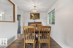 Dining area featuring warm wood-finish flooring, a window offering natural light, and a ceiling-mounted light fixture - 