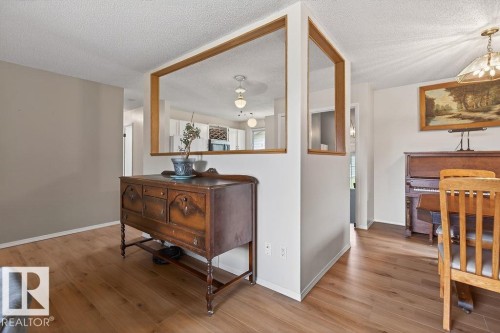 Open-concept living area featuring light wood-finish flooring, a pass-through window with wood trim, and neutral wall tones - 123 Grandin Drive, Morinville, AB 