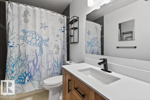 Bathroom featuring a wood-finish vanity with a white countertop and integrated sink, matte black faucet, and a large wall-mounted mirror - 123 Grandin Drive, Morinville, AB 