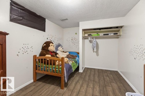 Room featuring wood-finish flooring, white baseboards, and a built-in closet with shelving and a hanging rod - 123 Grandin Drive, Morinville, AB 