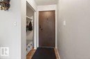 Entryway featuring a dark wood-finish door, light wood-finish flooring, and a built-in storage bench with shelving - 123 Grandin Drive, Morinville, AB 