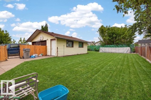 Expansive backyard featuring a manicured lawn, a detached garage, and wood privacy fencing - 123 Grandin Drive, Morinville, AB 