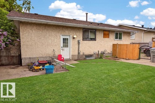 Expansive green lawn with a stucco exterior, multiple windows, a rear entry door, and a brown shingle roof - 123 Grandin Drive, Morinville, AB 