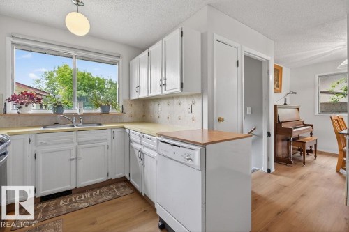 Kitchen featuring white cabinetry, a double basin stainless steel sink, and light-toned countertops - 123 Grandin Drive, Morinville, AB 