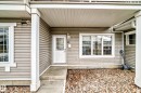 Front entry featuring a white door with upper glass panel, an exterior light fixture, and a house number - 53 150 Edwards Drive, Edmonton, AB 