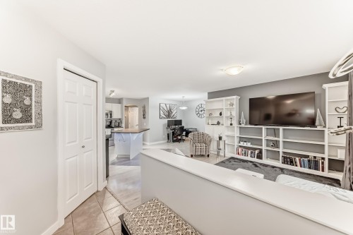 Open-concept living area featuring a built-in media center with extensive shelving, light gray wall paint, and recessed lighting - 53 150 Edwards Drive, Edmonton, AB 