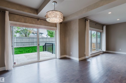 Expansive living space featuring wood-finish flooring, recessed lighting, and a decorative drum pendant light - 1957 Ainslie Link, Edmonton, AB 