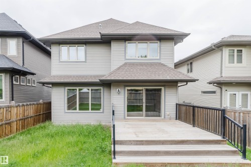 Rear elevation featuring a spacious wooden deck with dark railings, siding exterior, and multiple windows - 1957 Ainslie Link, Edmonton, AB 