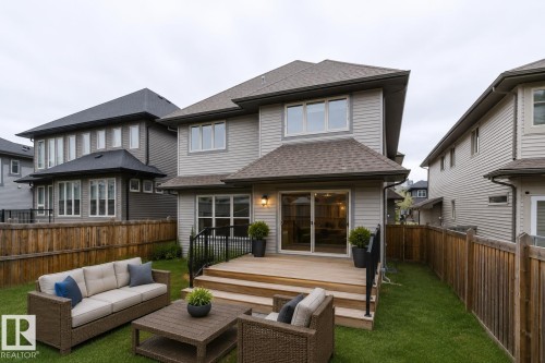 Spacious backyard with a wooden deck featuring black wrought iron railings - 1957 Ainslie Link, Edmonton, AB 