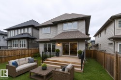 Spacious backyard with a wooden deck featuring black wrought iron railings - 