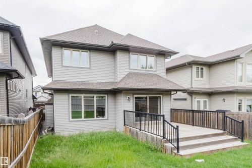 Rear exterior featuring a wooden deck with black metal railings and steps - 1957 Ainslie Link, Edmonton, AB 