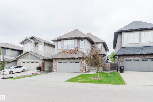 Modern two-story residence featuring a combination of light gray siding and stone veneer accents - 1957 Ainslie Link, Edmonton, AB 