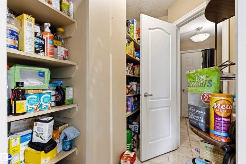 Kitchen pantry featuring extensive built-in shelving, a solid white door, and tiled flooring - 32 Lamplight Bay, Spruce Grove, AB 