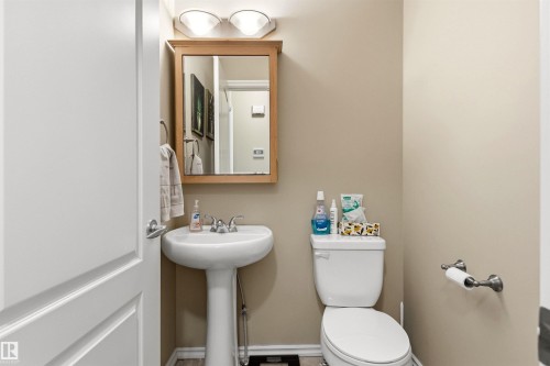 Pedestal sink with chrome faucet, framed mirror with integrated lighting, and neutral wall paint - 32 Lamplight Bay, Spruce Grove, AB 