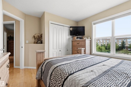Bedroom featuring light wood-finish flooring, a large window, and a built-in closet with bi-fold doors - 32 Lamplight Bay, Spruce Grove, AB 