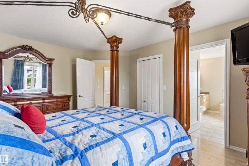 Bedroom featuring light-toned wall paint and wood-finish flooring - 32 Lamplight Bay, Spruce Grove, AB 