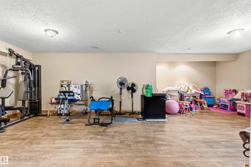 Expansive room featuring wood-finish flooring, recessed lighting, and neutral wall tones - 32 Lamplight Bay, Spruce Grove, AB 