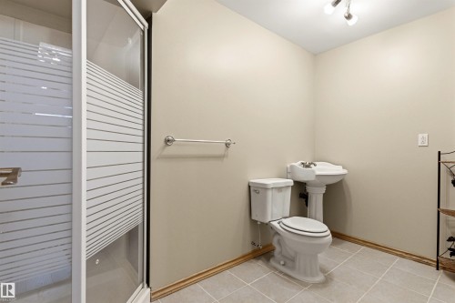 Bathroom featuring a glass-enclosed shower with frosted detailing, a pedestal sink, and a toilet - 32 Lamplight Bay, Spruce Grove, AB 