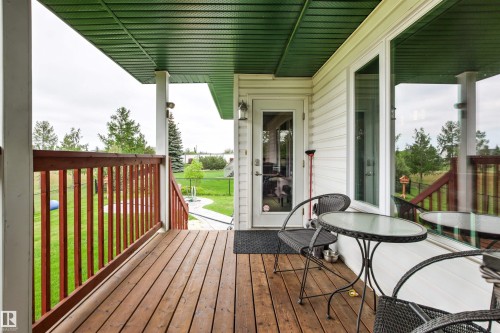 Expansive wood-finish deck with a wood railing and white support columns - 32 Lamplight Bay, Spruce Grove, AB 