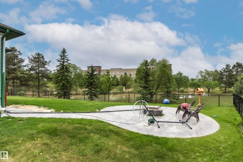 Expansive backyard featuring a curved concrete patio and a built-in stone fire pit - 32 Lamplight Bay, Spruce Grove, AB 