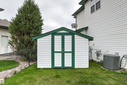 Detached storage shed featuring white siding and green trim - 32 Lamplight Bay, Spruce Grove, AB 