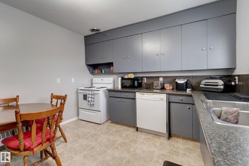 Kitchen featuring extensive gray cabinetry with ample storage, a white electric range, and a white dishwasher - 10524 78 Street, Edmonton, AB - Indoor Photo Showing Kitchen With Double Sink