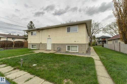 Two-story exterior featuring stucco siding with a concrete block foundation, white framed windows, and a paved walkway - 10524 78 Street, Edmonton, AB - Outdoor