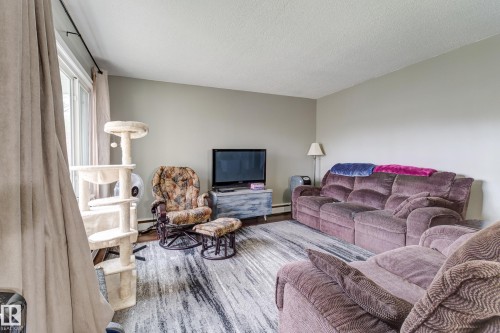 Spacious living area featuring light gray wall paint, white trim, and a window with neutral drapes - 10524 78 Street, Edmonton, AB - Indoor Photo Showing Living Room