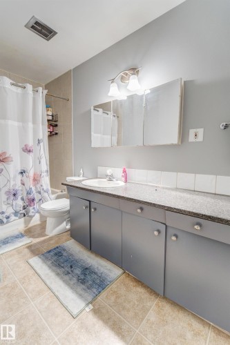 Bathroom featuring a full vanity with an integrated sink, granite-finish countertop, and gray cabinetry - 10524 78 Street, Edmonton, AB - Indoor Photo Showing Bathroom