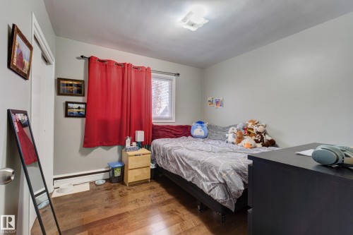 Bright interior space featuring wood-finish flooring, light grey wall paint, and a white ceiling with a flush-mount light fixture - 10524 78 Street, Edmonton, AB - Indoor Photo Showing Bedroom