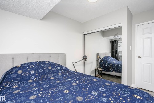 Bedroom featuring light gray walls, wood-finish flooring, a white paneled door, and mirrored sliding closet doors - 3103 109 Street, Edmonton, AB 