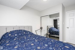Bedroom featuring light gray walls, wood-finish flooring, a white paneled door, and mirrored sliding closet doors - 