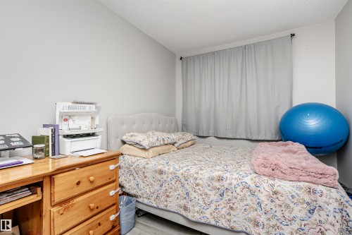 Bedroom featuring light gray wall paint, a window with drapery, and wood-finish flooring - 3103 109 Street, Edmonton, AB 
