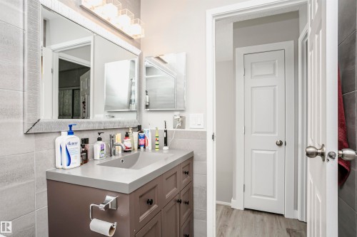 Bathroom vanity with a gray countertop, an integrated sink, and dark wood-finish cabinetry - 3103 109 Street, Edmonton, AB 