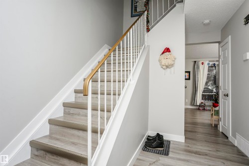 Staircase featuring wood-finish treads, white risers, and a white baluster with a golden-toned handrail - 3103 109 Street, Edmonton, AB 