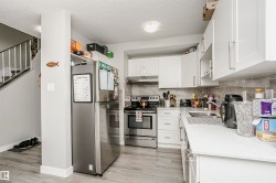 Modern kitchen featuring white cabinetry, a stainless steel electric range, and a dual-basin sink - 