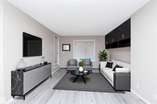 Living area featuring light wood-finish flooring, light-colored walls, and a large window with blinds - 108 530 Watt Boulevard, Edmonton, AB 