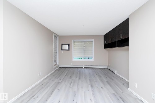 Spacious room featuring light wood-finish flooring, neutral wall paint, and a white ceiling - 108 530 Watt Boulevard, Edmonton, AB 