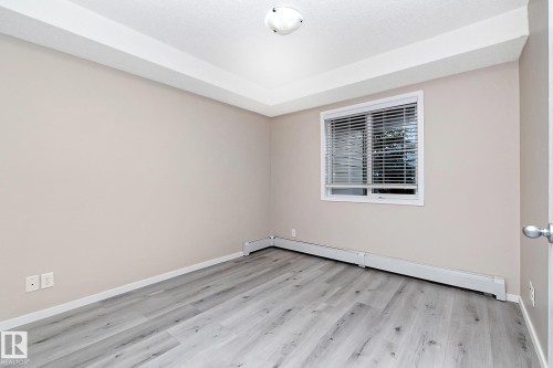 Light-filled interior featuring wood-finish flooring, neutral wall tones, and a window with horizontal blinds - 108 530 Watt Boulevard, Edmonton, AB 